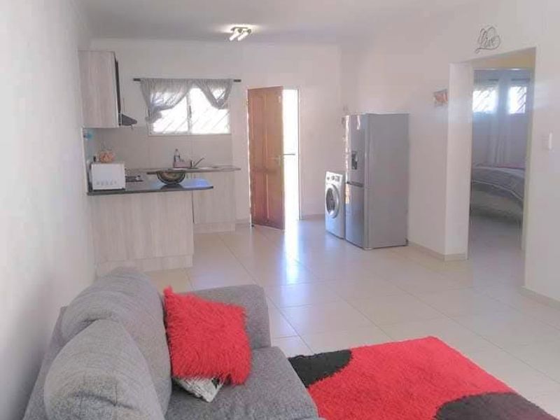 Open plan living area featuring tiled flooring and a functional kitchen space with built-in cabinetry and countertops.