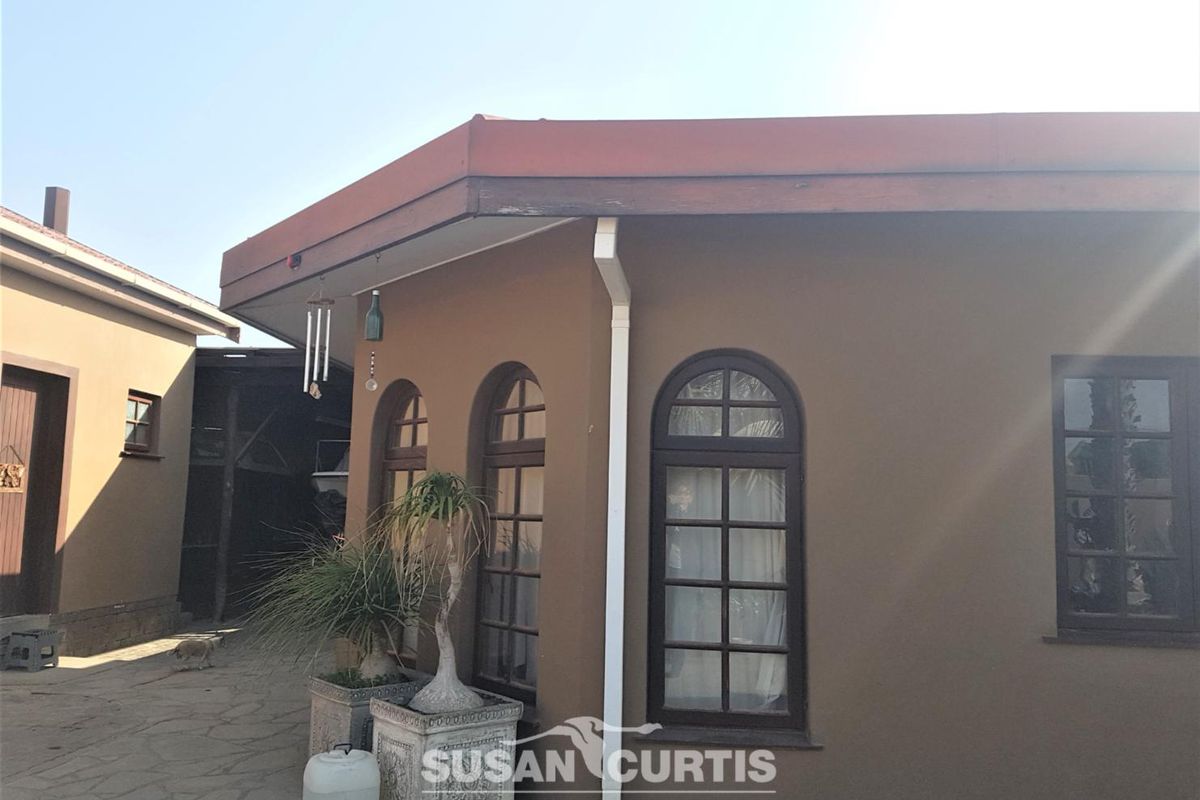 Exterior view of the property featuring arched windows, brown rendered walls, and a paved courtyard area.