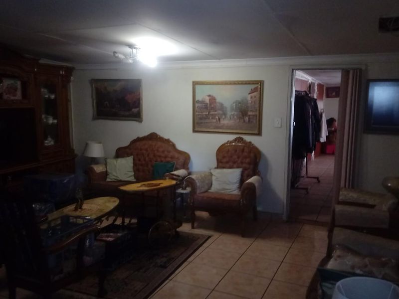 A living room area featuring tiled flooring and a folding door leading to an adjacent space, with a visible ceiling defect.