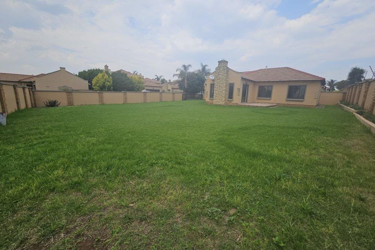 Spacious rear garden featuring a large lawn, perimeter boundary walls, and a stone-clad chimney on the rear elevation of the townhouse.