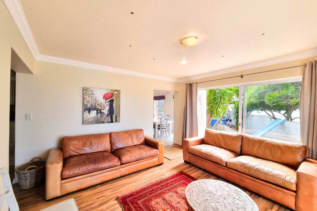 Spacious living room featuring wood-look flooring, crown molding, recessed lighting, and large sliding glass doors providing natural light and garden access.