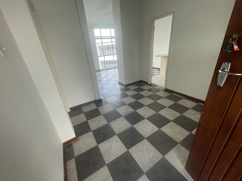 An empty entrance foyer featuring a checkered tile floor, leading into the main living area and adjacent rooms.