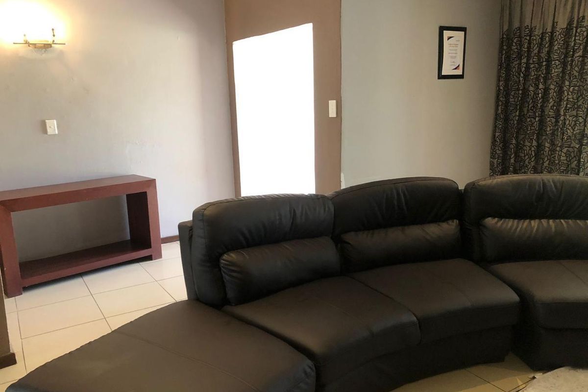 A living room area featuring tiled flooring and wall-mounted lighting fixtures, providing a functional space for relaxation.