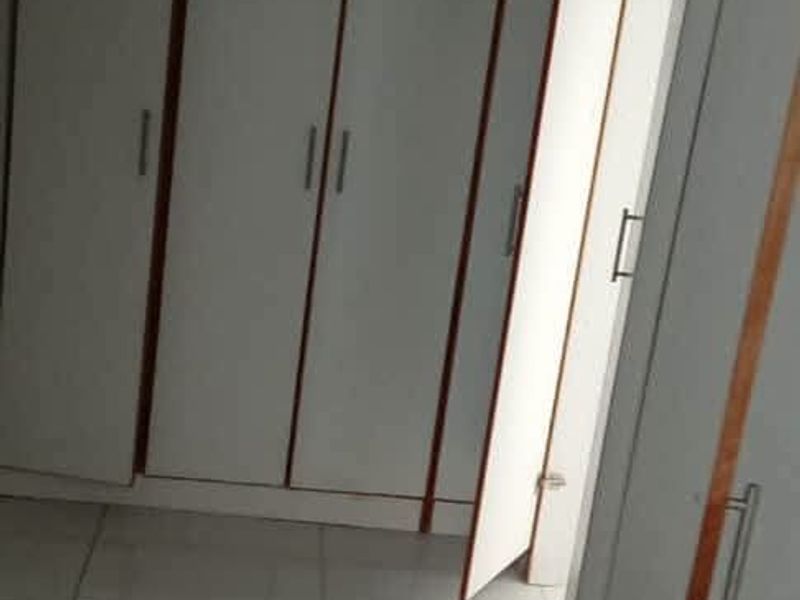 A bedroom featuring white built-in cupboards with wooden trim and light-colored tiled flooring.