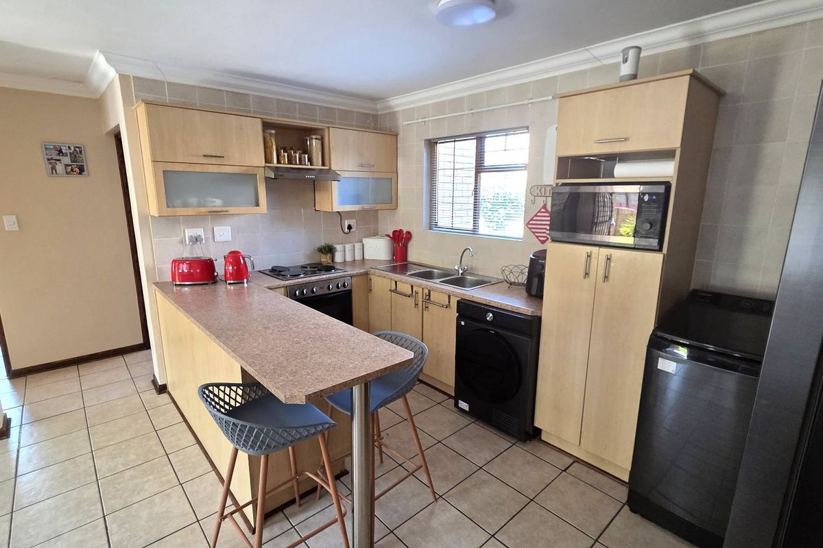 Functional kitchen featuring light wood cabinetry, laminate countertops, a breakfast nook, and tiled finishes, offering a practical layout for daily meal preparation.