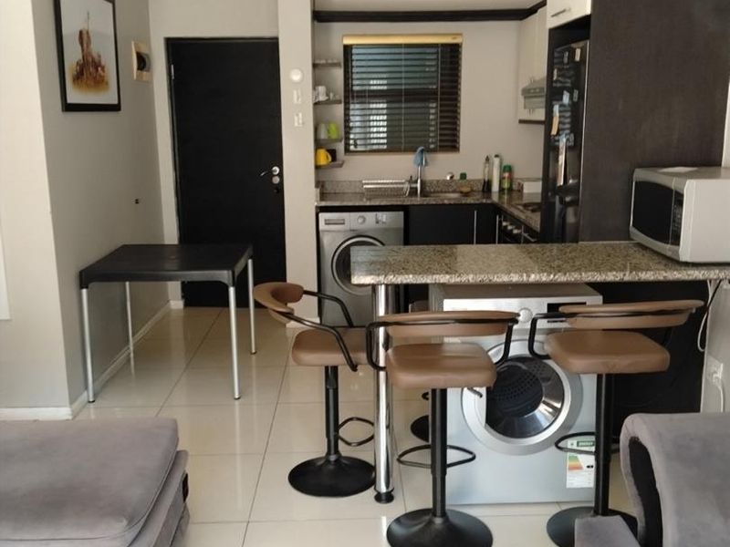 Open plan living and kitchen area featuring tiled floors, granite countertops, breakfast bar, and an integrated air conditioning unit.