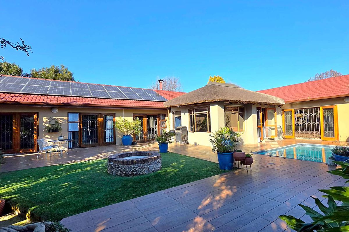 Spacious rear exterior featuring a tiled patio, swimming pool, built-in fire pit, and solar panels installed on the roof.