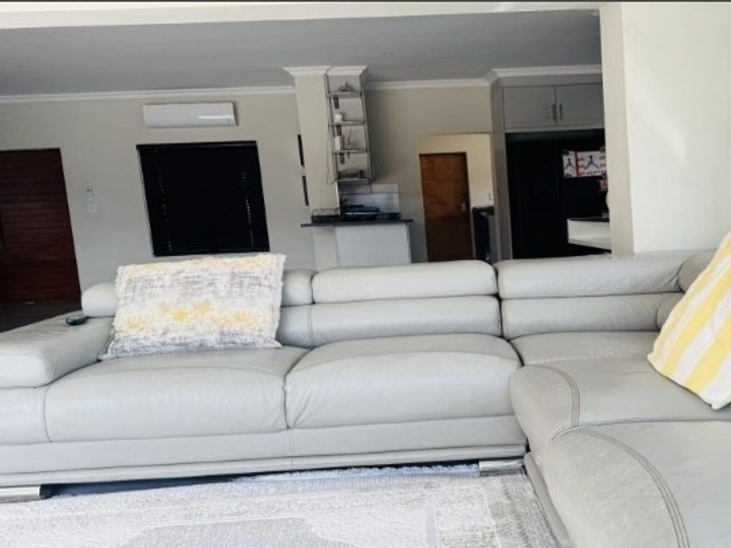 Spacious open-plan living area featuring neutral walls, coving, and integrated air conditioning, seamlessly connecting to the kitchen and dining zones.
