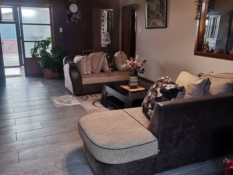 A spacious living room featuring modern grey tiled flooring, high ceilings, and a sliding glass door providing access to the outdoor area.