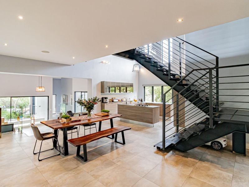 Spacious open-plan living area featuring a modern kitchen, dining space, and a striking architectural metal staircase with integrated lighting.