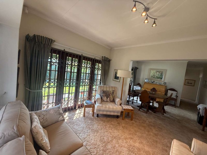 Open plan living and dining area featuring carpeted flooring and large sliding doors with security gates providing access to the outdoor space.