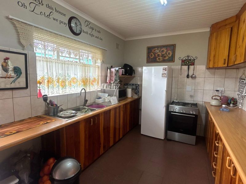 A functional kitchen featuring wooden cabinetry, laminate countertops, tiled backsplash, and a freestanding gas stove with a tongue and groove ceiling.