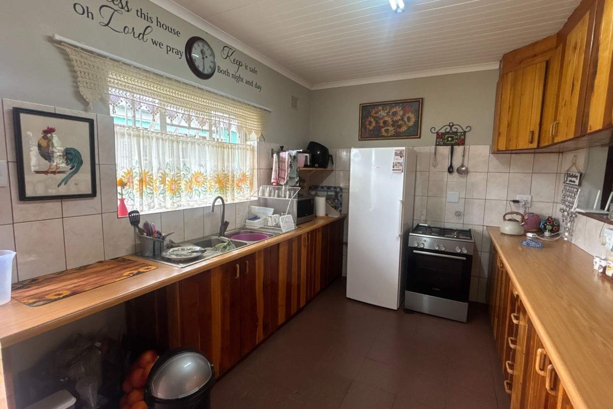 A functional kitchen featuring wooden cabinetry, laminate countertops, tiled backsplash, and a freestanding gas stove with a tongue and groove ceiling.