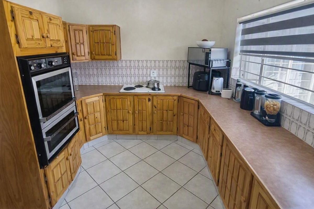 A functional kitchen featuring traditional wooden cabinetry, laminate countertops, an eye-level oven, and an electric hob with tiled splashback.
