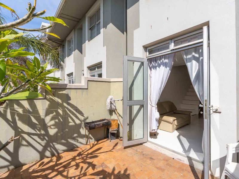A private rear patio area featuring paved flooring and direct access to the interior living space through an aluminium framed glass door.