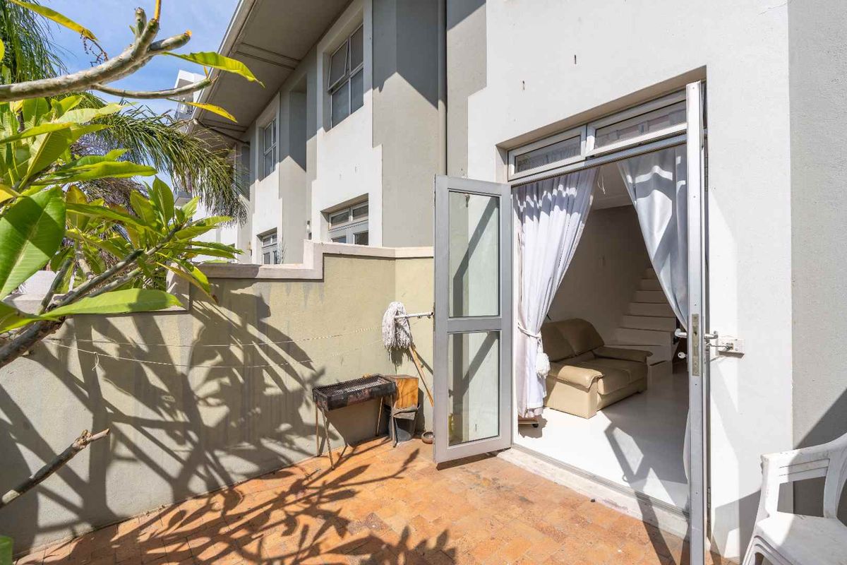 A private rear patio area featuring paved flooring and direct access to the interior living space through an aluminium framed glass door.