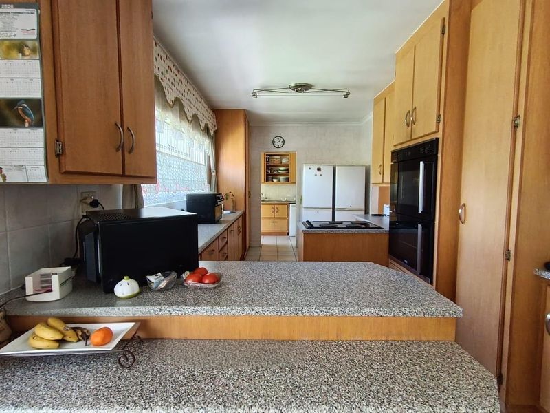 A functional kitchen featuring wood-tone cabinetry, granite-look laminate countertops, and a built-in double oven, offering a traditional layout with ample storage space.