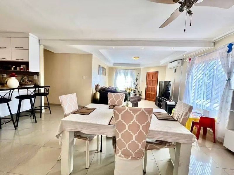 Spacious open-plan living and dining area featuring tiled flooring, recessed lighting, a ceiling fan, and an integrated kitchen with a breakfast bar.