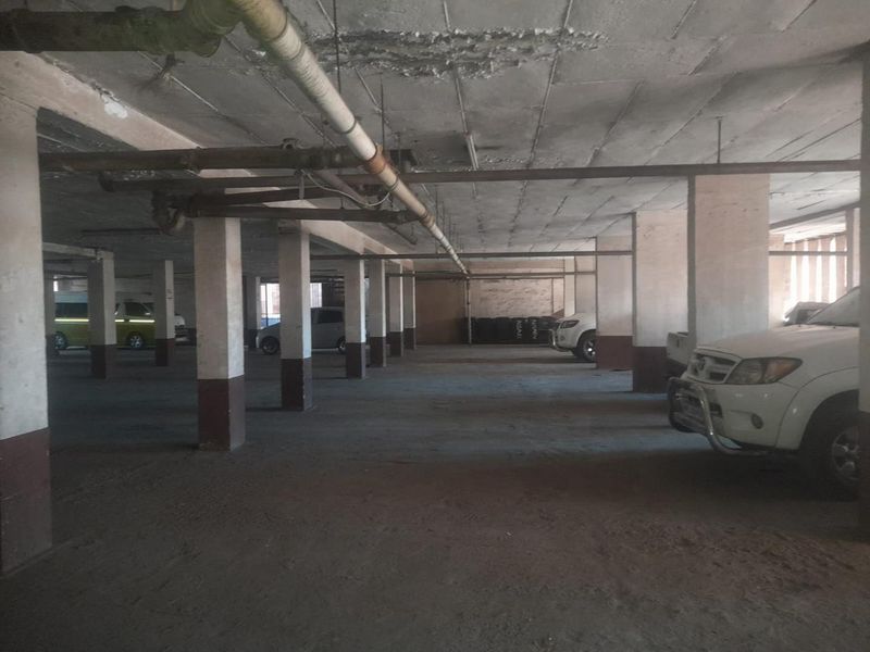 Underground parking garage featuring concrete columns, exposed overhead plumbing, and a concrete floor surface.