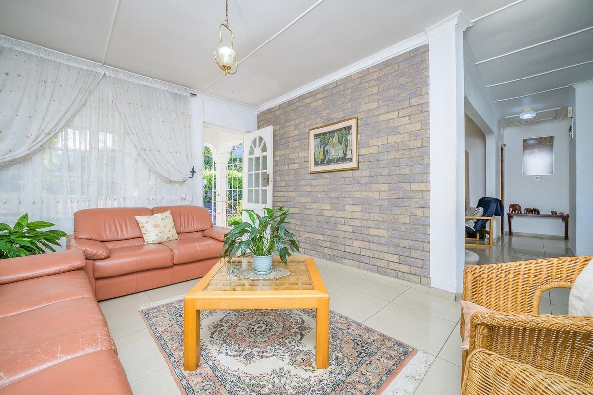 A living room featuring a prominent exposed brick feature wall, tiled flooring, and coved ceilings, with direct access to the exterior.
