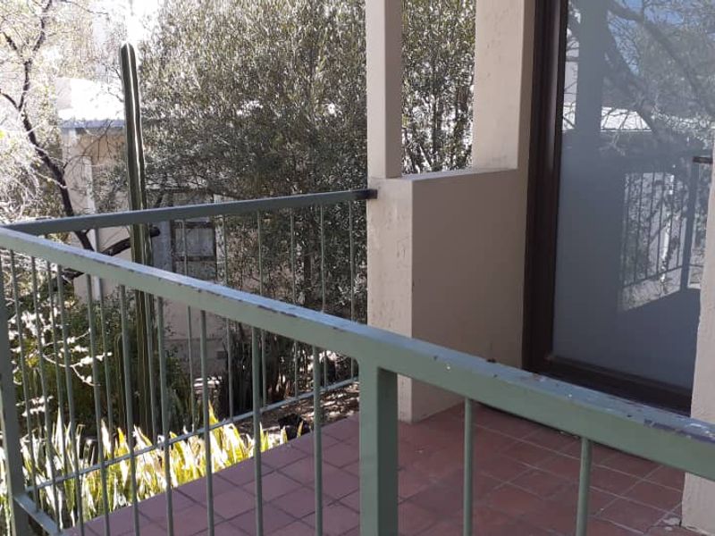 A private balcony featuring tiled flooring and a metal railing, providing an outdoor space accessible through a sliding glass door.