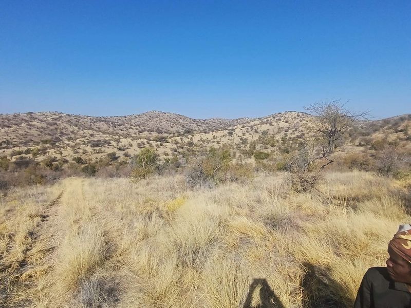 Expansive landscape view of the surrounding hilly farm terrain under a clear blue sky.