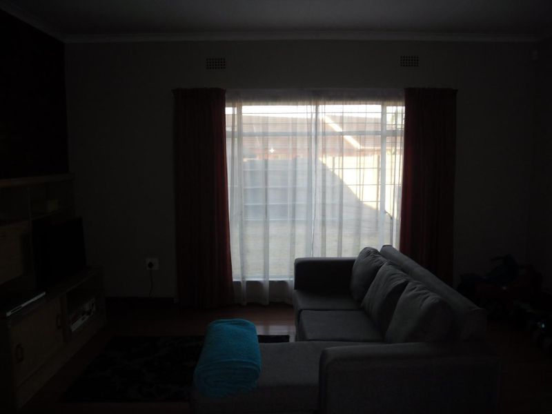 A living room featuring large windows that provide natural light, finished with laminate flooring.