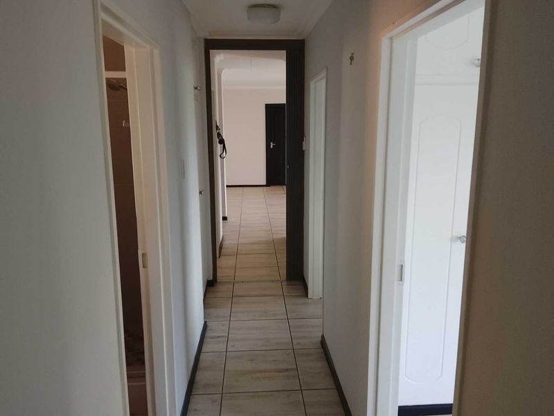 A functional hallway featuring neutral tiled flooring and multiple internal doorways providing access to various rooms within the townhouse.
