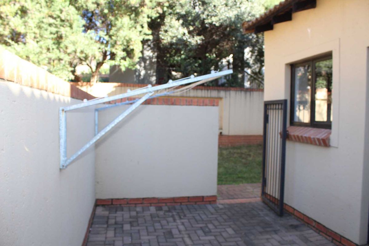 A private rear courtyard featuring paved flooring, a wall-mounted clothesline, and secure access gate, providing a functional outdoor utility space.