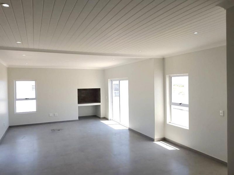 Spacious open-plan living area featuring polished concrete floors, a built-in fireplace, and a modern tongue and groove ceiling with recessed lighting.