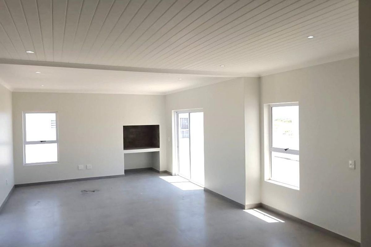 Spacious open-plan living area featuring polished concrete floors, a built-in fireplace, and a modern tongue and groove ceiling with recessed lighting.