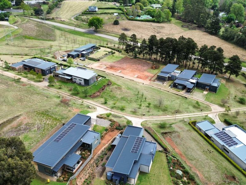 Aerial view of a residential estate featuring modern homes with solar panels, paved access roads, and established landscaped grounds.