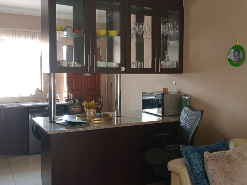 Open plan kitchen and living area featuring dark wood cabinetry, granite countertops, a breakfast bar, and tiled flooring.