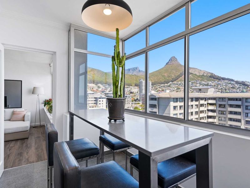 Enclosed balcony area featuring expansive windows with panoramic mountain and city views, providing a bright and versatile space.
