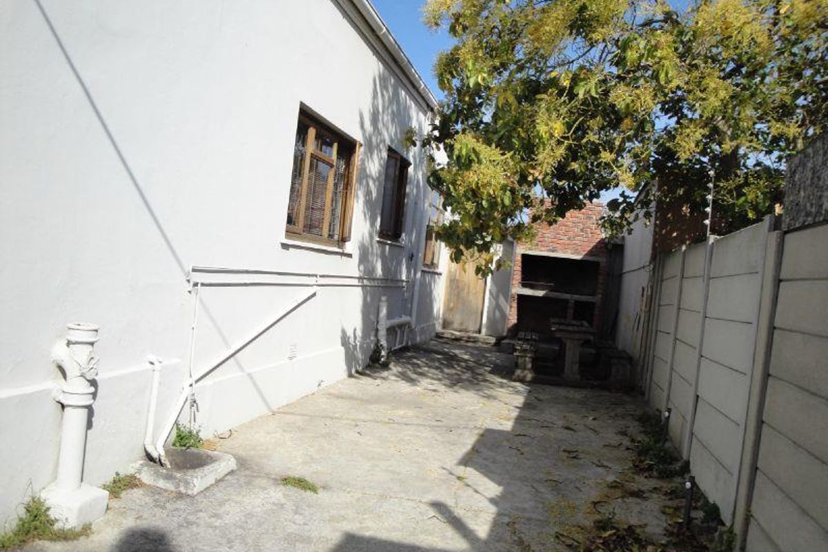 Rear exterior area featuring a built-in braai, concrete paving, and perimeter precast walling.