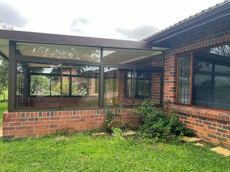 Rear exterior view of a brick townhouse featuring a sunroom extension with large sliding glass doors and aluminum framing.
