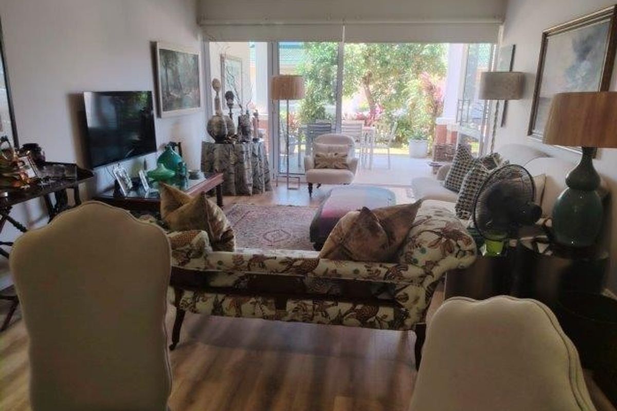 A comfortable living room featuring laminate flooring and large sliding glass doors that provide natural light and access to the outdoor patio area.