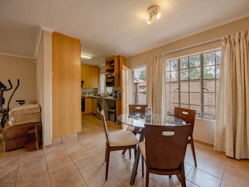 Open-plan living and dining area featuring tiled flooring, natural light, and an adjoining kitchen with built-in cabinetry.
