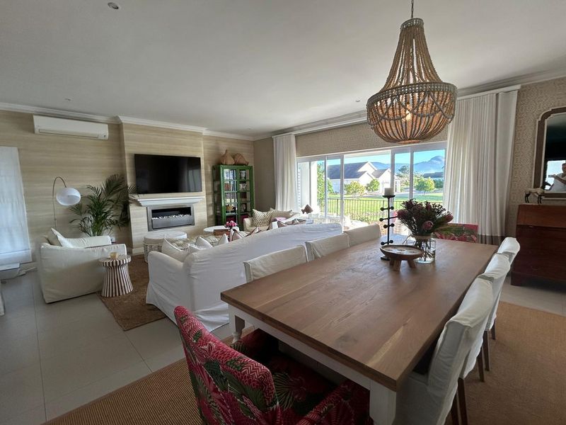 Spacious open-plan living and dining area featuring a built-in fireplace, split-system air conditioning, and large sliding doors leading to an outdoor patio.