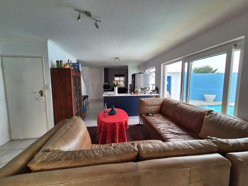 Open-plan living and kitchen area featuring tiled floors, modern kitchen island, and large sliding doors providing direct access to the outdoor pool area.