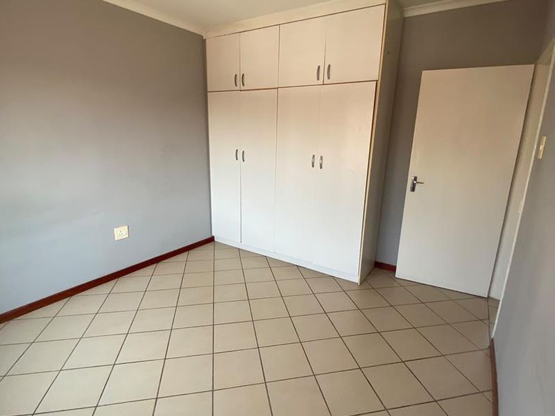 An empty bedroom featuring tiled flooring and built-in cupboards, providing a neutral canvas for potential interior design updates.