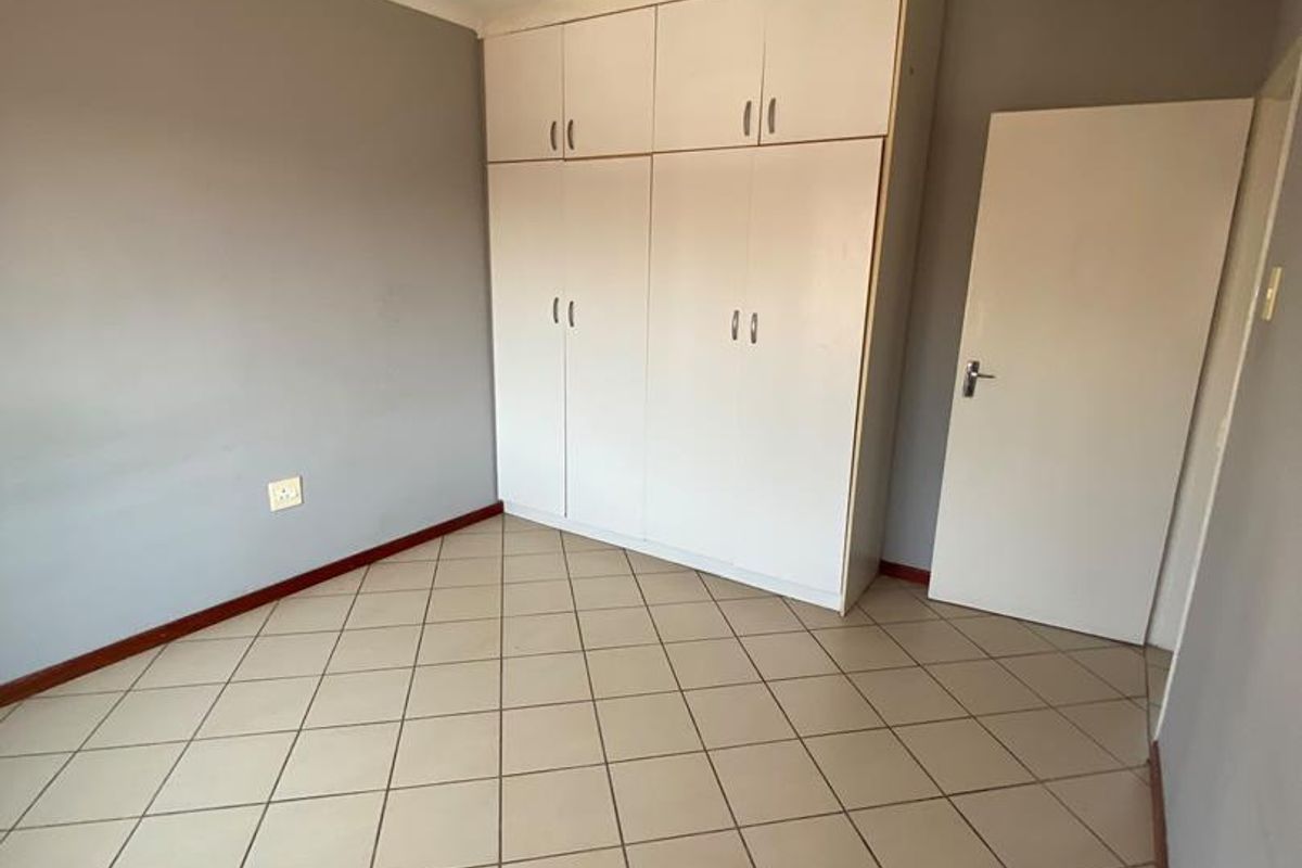 An empty bedroom featuring tiled flooring and built-in cupboards, providing a neutral canvas for potential interior design updates.