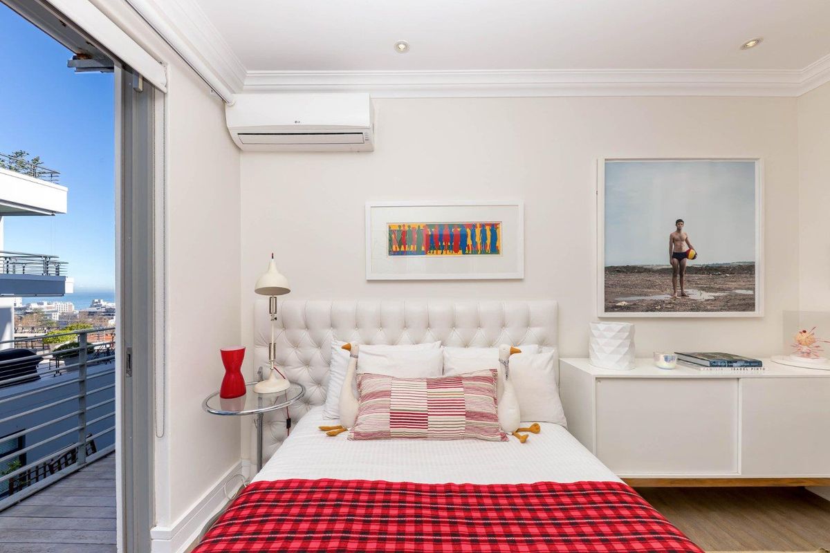 A well-maintained bedroom featuring a split-system air conditioner, recessed lighting, and direct access to a private balcony with city views.
