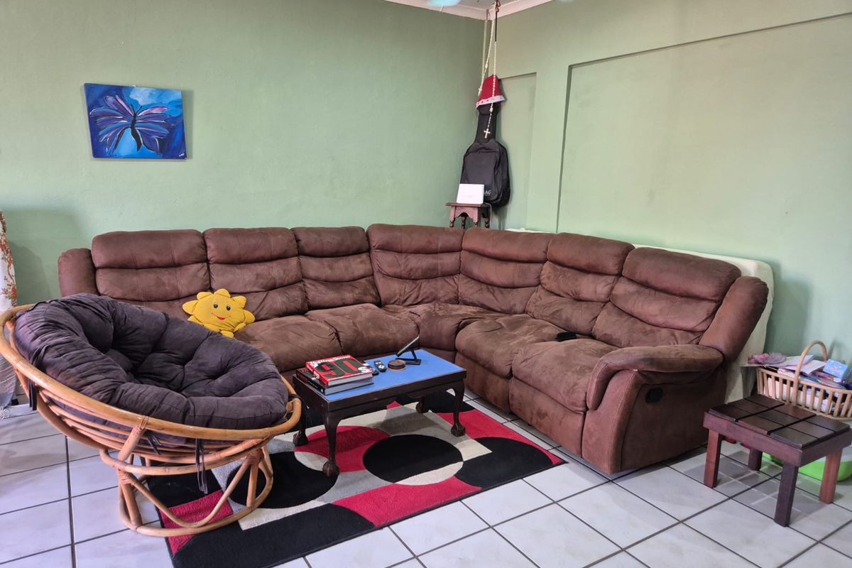A living room featuring tiled flooring, a ceiling fan, and coved ceiling details, providing a functional space for relaxation.