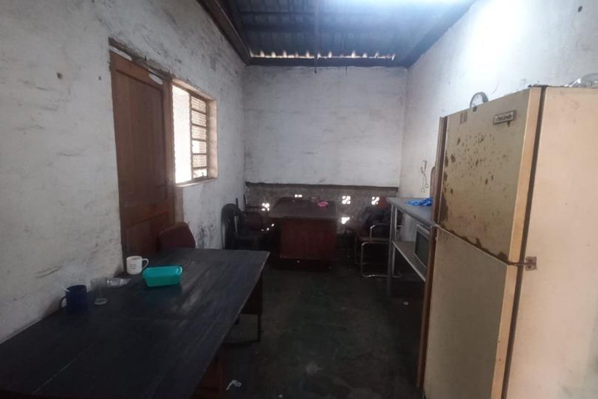 A basic industrial kitchen space featuring exposed roof structure, ventilation blocks, and worn wall finishes, offering potential for renovation and modernization.