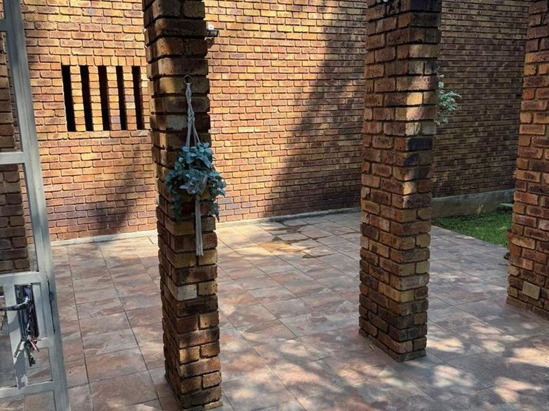An open-air patio area featuring face brick pillars and tiled flooring, providing a private outdoor space for relaxation.