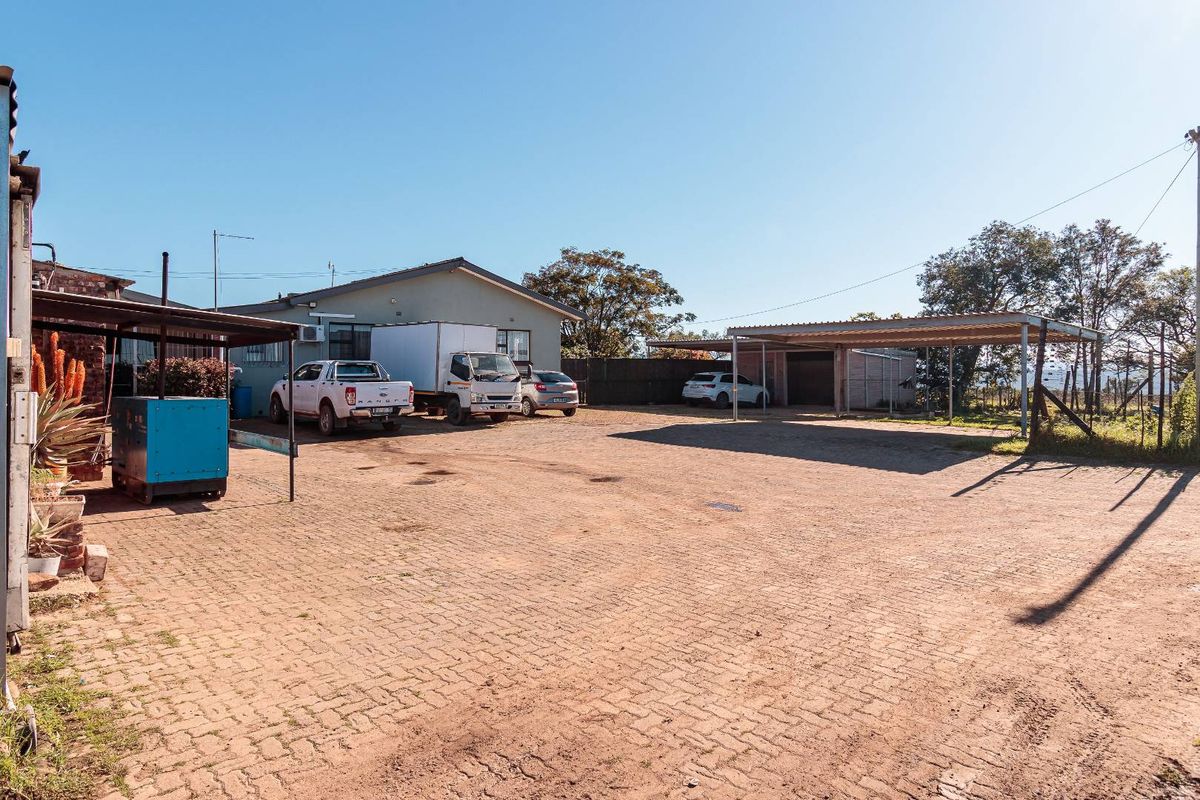 Spacious paved yard area featuring a large carport structure and access to the main dwelling and outbuildings on the farm property.