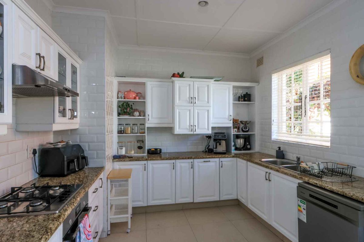 A well-maintained kitchen featuring white cabinetry, granite countertops, subway tile backsplash, and integrated appliances including a gas hob and oven.