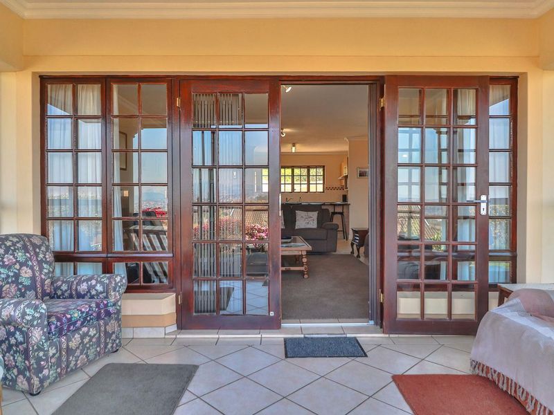 A covered patio area featuring tiled flooring and large wooden-framed glass doors that provide access to the interior living space.