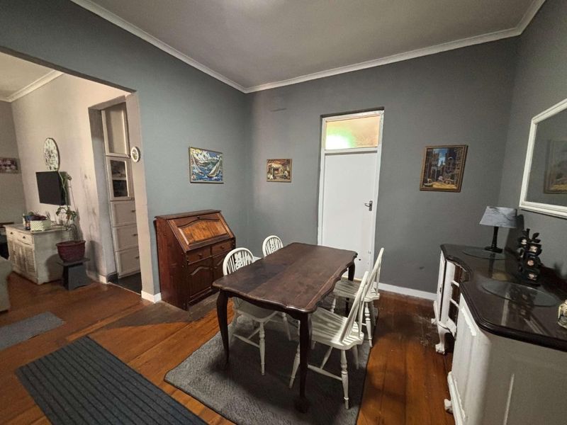 Dining room featuring original hardwood flooring, coved ceilings, and neutral grey wall tones, providing a classic foundation for interior updates.